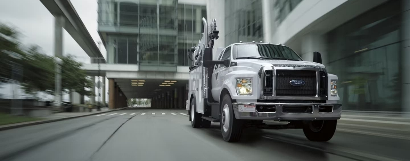 White 2024 Ford F-750 SuperCab driving on a cityy street